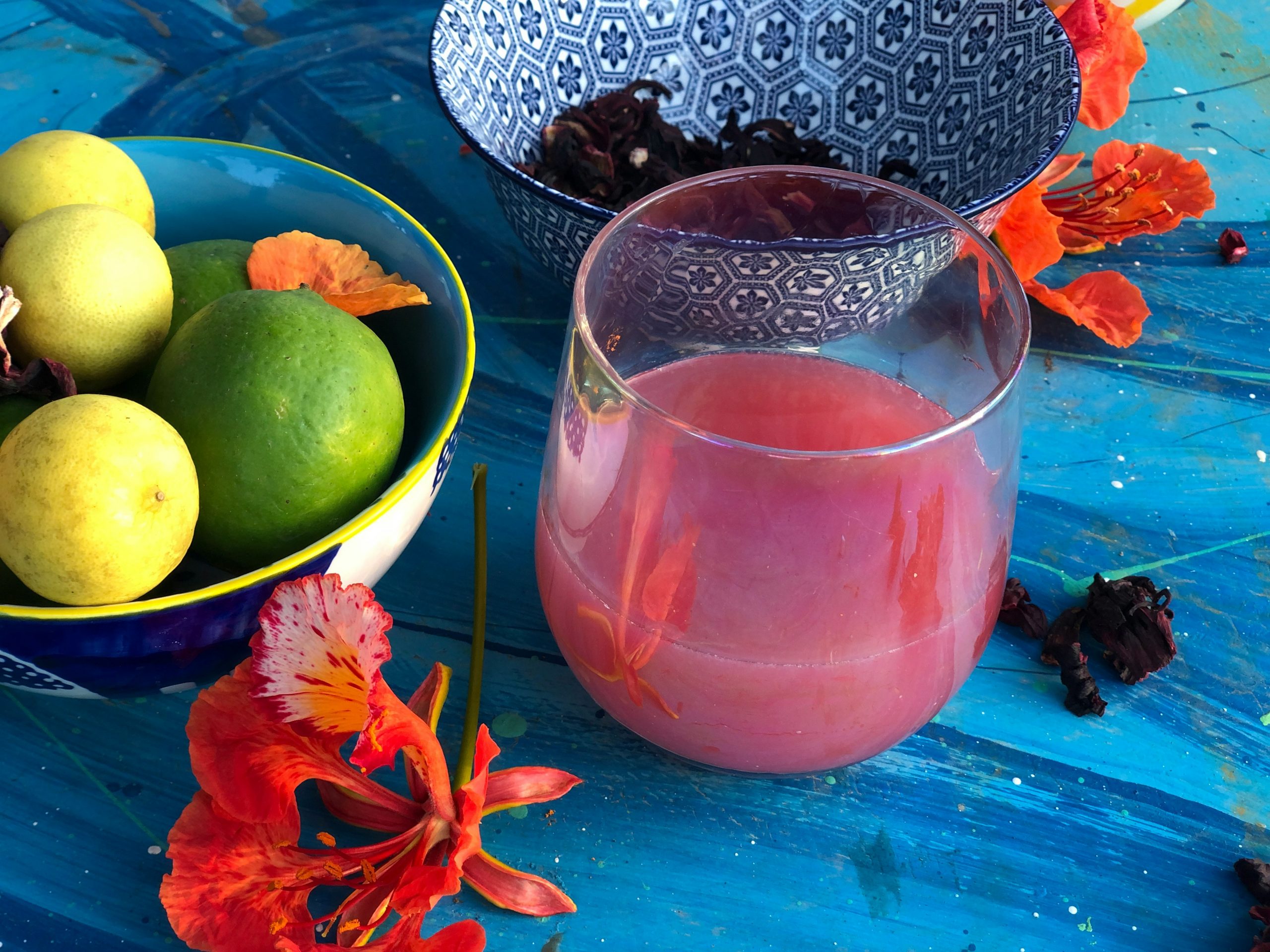 pink collagen drink in a glass, with a bowl of fruits next to it